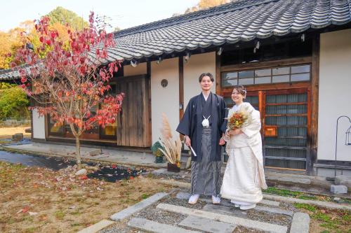 a man and a woman standing in front of a building at しまなみ宿Gyoku in Imabari