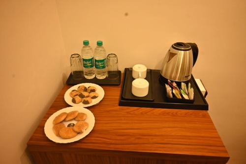 a table with two plates of pastries and bottles of water at Swet Palash Resort in Purulia