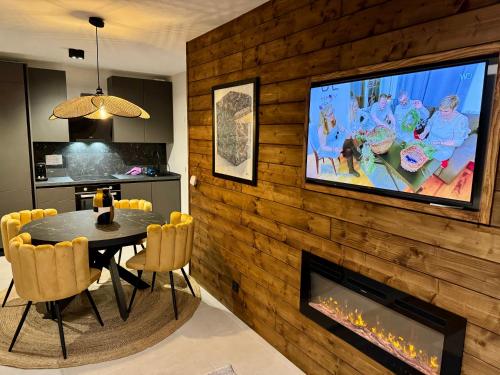 Un comedor con una mesa y un televisor en la pared. en AURON 2P NEUF - Le Mont d'Auron, en Auron