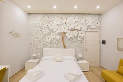 - une chambre avec un lit blanc et une fresque murale sur les arbres dans l'établissement Enchanting Suites Salerno, à Salerne