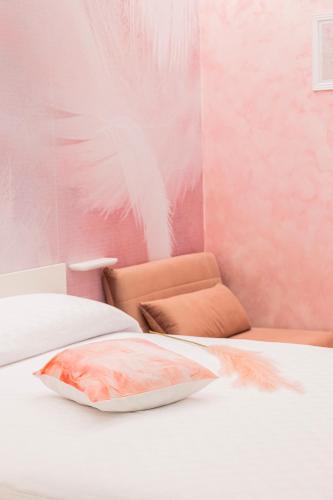 a pink bedroom with a bed with a pillow on it at Enchanting Suites Salerno in Salerno