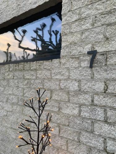 a brick wall with a tree in front of a window at Guestsuite The Nest in Wielsbeke