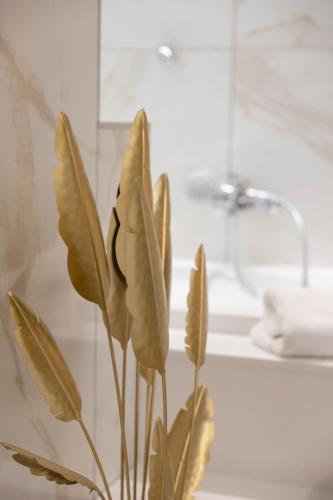 a vase with a plant in front of a bathroom at Enchanting Suites Salerno in Salerno