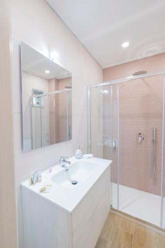 a white bathroom with a sink and a shower at Enchanting Suites Salerno in Salerno