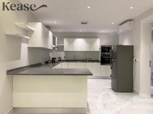 una cucina con armadi bianchi e frigorifero in acciaio inossidabile di Kease Yasmin A-3 Royal touch AG44 a Riyad