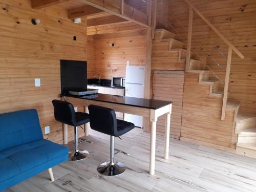 eine Küche mit einem Tisch, 2 Stühlen und einem Kühlschrank in der Unterkunft Cabaña nórdica en la naturaleza in Punta Ballena