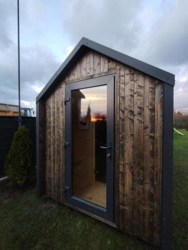 a small shed with a door in the grass at Hygge Domki in Junoszyno