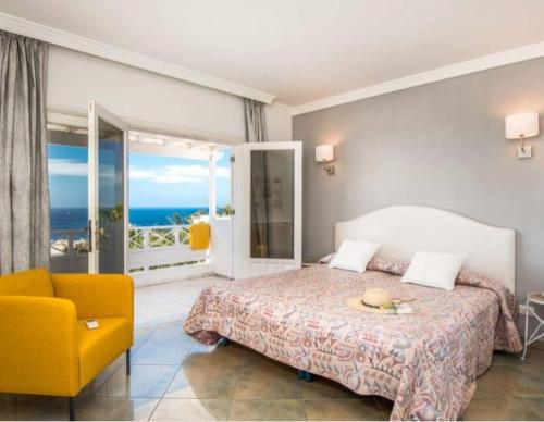 a bedroom with a large bed and a yellow chair at Villa Arcelia in Puerto del Carmen