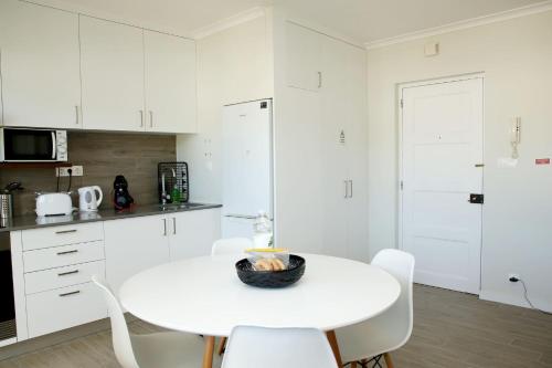 a white kitchen with a white table and white chairs at Apartamento Mãe de Deus in Ponta Delgada