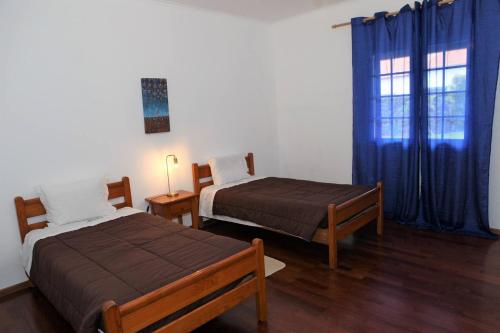 a bedroom with two beds and a window with blue curtains at Batalha House in Ponta Delgada