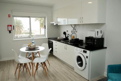 a kitchen with a table and a washing machine at Apartamento Mãe de Deus in Ponta Delgada