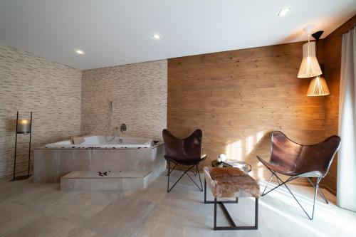 een badkamer met een bad en 2 stoelen bij Chalet Chäserrugg in Wildhaus