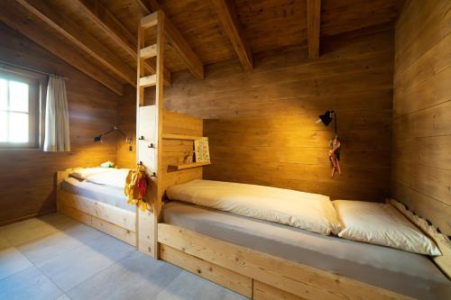 two beds in a room with wooden walls at Chalet Chäserrugg in Wildhaus