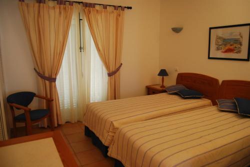 een slaapkamer met een bed, een stoel en een raam bij Pestana Golf Resort - T2 71d in Carvoeiro