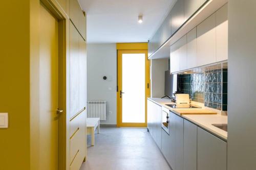 a kitchen with white cabinets and a yellow door at Estudio moderno y acogedor en Madrid Rio nº1 in Madrid
