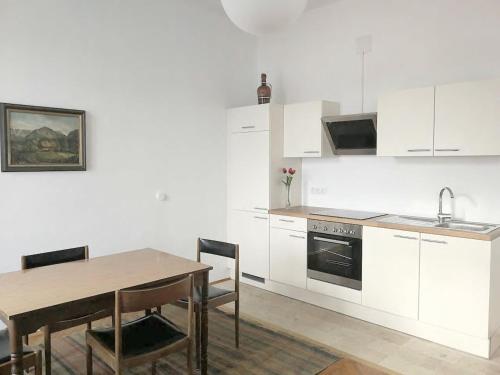 eine Küche mit weißen Schränken und einem Holztisch mit einem Esszimmer in der Unterkunft Schöne einfache Wohnung in Jugendstilhaus in Feistritz an der Drau