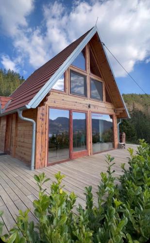 a cabin with large windows and a wooden deck at Zaovinska idila in Bjeluša