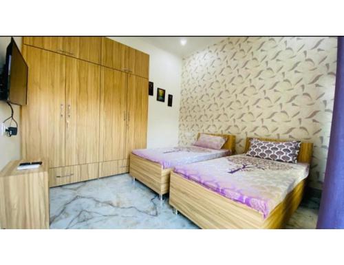 2 camas en una habitación con armarios de madera en Saini Guest House , Gurdaspur, en Gurdāspur