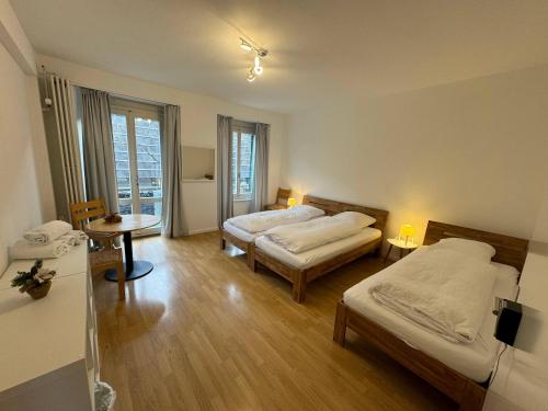 um quarto com duas camas e uma mesa com candeeiros em Downtown Apartments em Interlaken