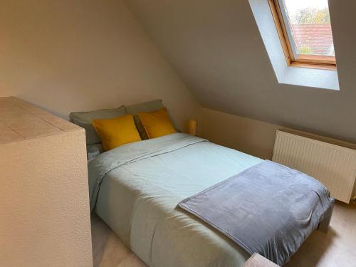 1 dormitorio con 1 cama con almohadas amarillas en Les pampas, en Montbronn