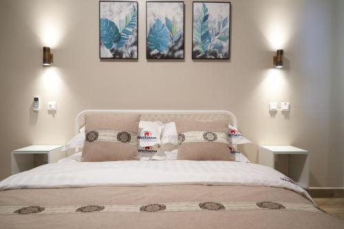 a bedroom with a bed with three pictures on the wall at Westwood Residences in Arusha