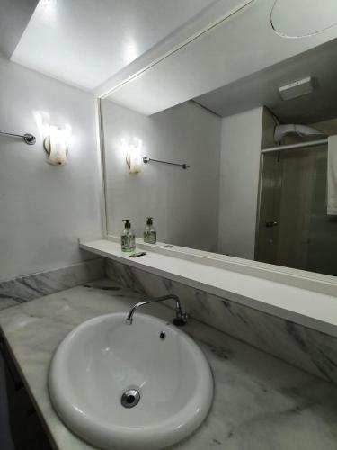 y baño con lavabo blanco y espejo. en Flat Wall Street, en Caxias do Sul