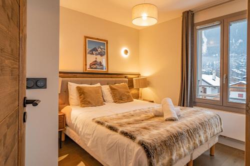 une chambre avec un lit et une grande fenêtre dans l'établissement Perle Blanche - Brand New 2 bedroom apartment perfectly located, à Chamonix-Mont-Blanc