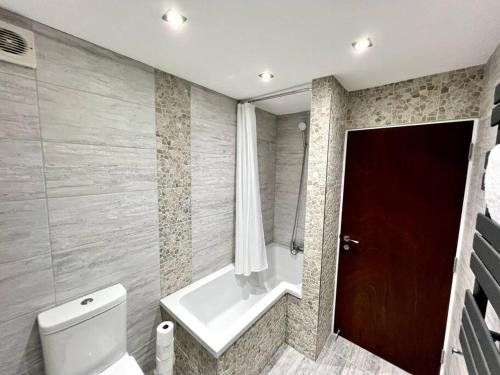 a bathroom with a tub and a toilet and a window at Perfect Stay For Family & Contractors With Free Parking in Luton