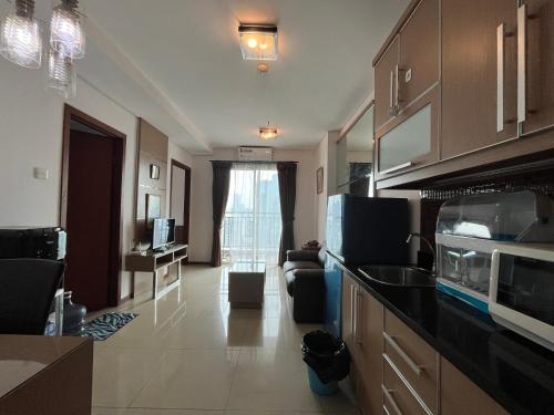 a kitchen with a counter top and a living room at Comfy 1BR At Central ( City View ) in Jakarta
