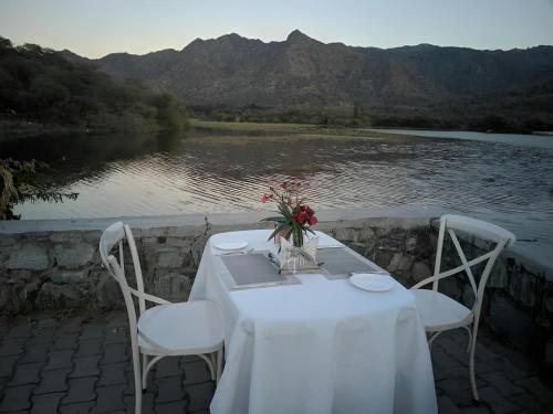 a table with two chairs and a table with flowers at Shivika Lake Hotel Ranakpur in Sādri