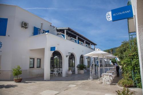 a white building with tables and chairs and an umbrella at Hotel Aleksandar in Budva