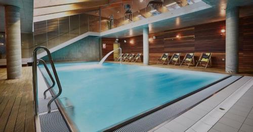 a large swimming pool with chairs in a building at Royal 111 in Kołobrzeg