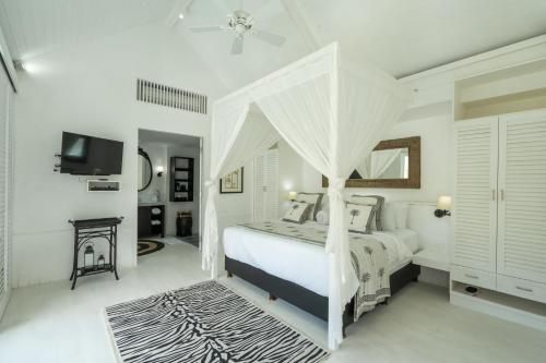a white bedroom with a bed with a canopy at White Horse Resort in Nusa Lembongan