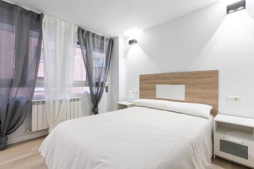 ein weißes Schlafzimmer mit einem großen Bett und einem Fenster in der Unterkunft APARTMENTS BOUTIQUE PALENCIA in Palencia