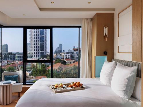a hotel room with a bed with a tray of food on it at Elkonin Tel Aviv - MGallery Hotel Collection in Tel Aviv