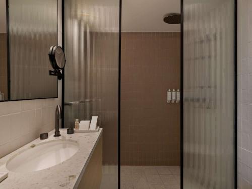 a bathroom with a sink and a shower at Elkonin Tel Aviv - MGallery Hotel Collection in Tel Aviv
