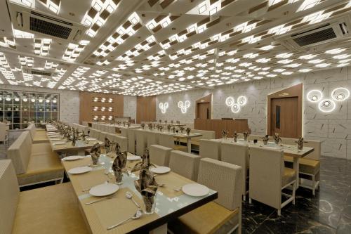 a dining room with tables and chairs and lights at HOTEL COMFY in Unjha