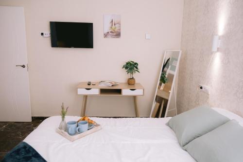 Habitación con cama, TV y mesa. en Piso compartido Delyrent, Reja, en Jaén