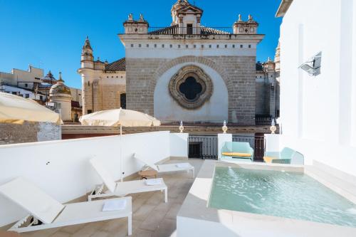eine Terrasse mit Stühlen und einen Pool vor einem Gebäude in der Unterkunft Ninesuites Cathedral in Sevilla