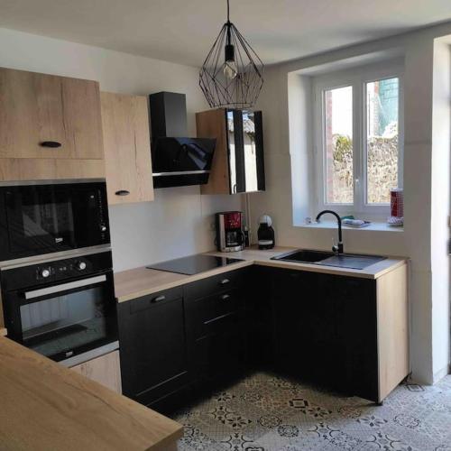 une cuisine avec un évier et une cuisinière dans l'établissement Maison de ville rénovée au cœur du Cotentin., à Périers