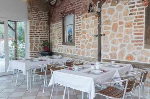 a restaurant with white tables and chairs and a brick wall at MB Pag Bed&Breakfast in Pag