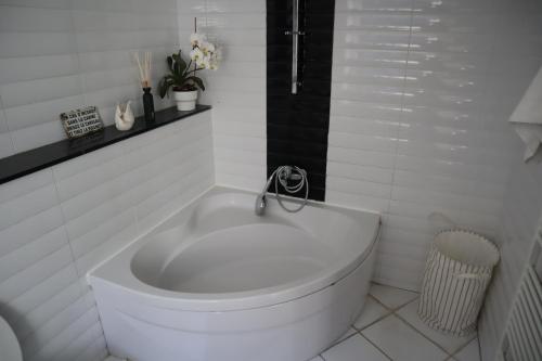 a white bath tub in a white tiled bathroom at Appartement 2 chambres grande terrasse centre de Bruxelles in Brussels