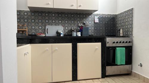 a kitchen with white cabinets and a black counter top at Stella Maris, Asilah medina in Asilah