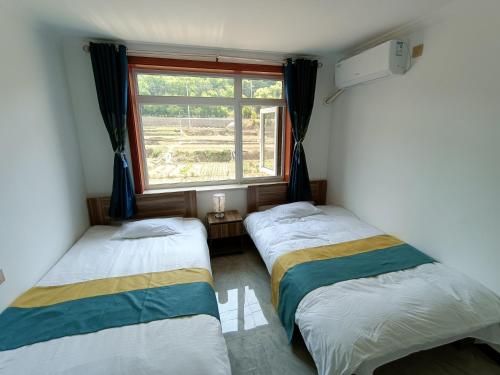 2 camas en una habitación con ventana en Gubeikou Great Wall Juxian Residents' Lodging, en Miyun