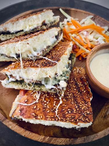 a wooden plate with three sandwiches and a bowl of sauce at Happiness Hostel Boracay in Boracay
