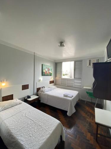 a bedroom with two beds and a flat screen tv at Oscar Palace Hotel - Centro de Tubarão in Tubarão