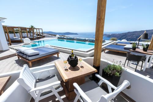 a patio with a table and chairs and a swimming pool at Amaze Suites in Imerovigli