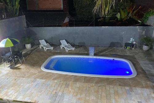 a large blue tub in a yard with two chairs and an umbrella at Casa de Praia com piscina in São Sebastião