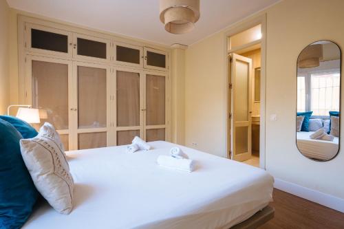 a bedroom with a white bed and a mirror at The Zentral Suites & Apartments in Seville