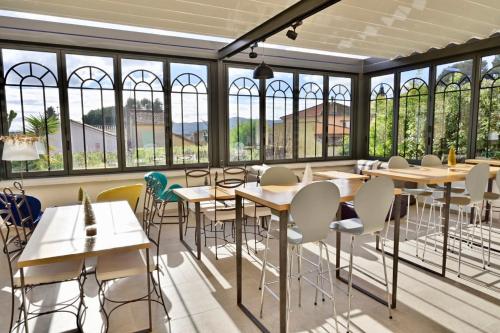 um restaurante com mesas, cadeiras e janelas em Hôtel La Petite Bohème em Le Lavandou